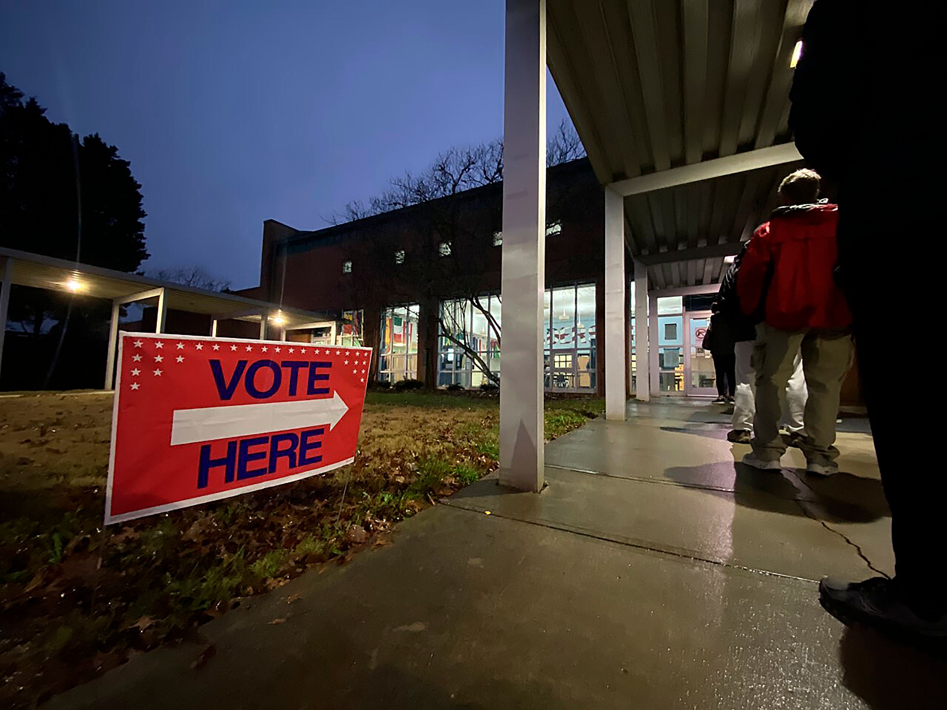 At a polling location in Johns Creek, Ga., voters in suburban Atlanta lined up before the polls opened on Tuesday, Dec. 6, 2022, to cast their ballot, undeterred by a 40-degree wind chill and steady rain. The line at Shakerag Elementary School moved swiftly. One voter called Election Day voting at this polling location, “smooth.” (AP Photo/Alex Sanz)